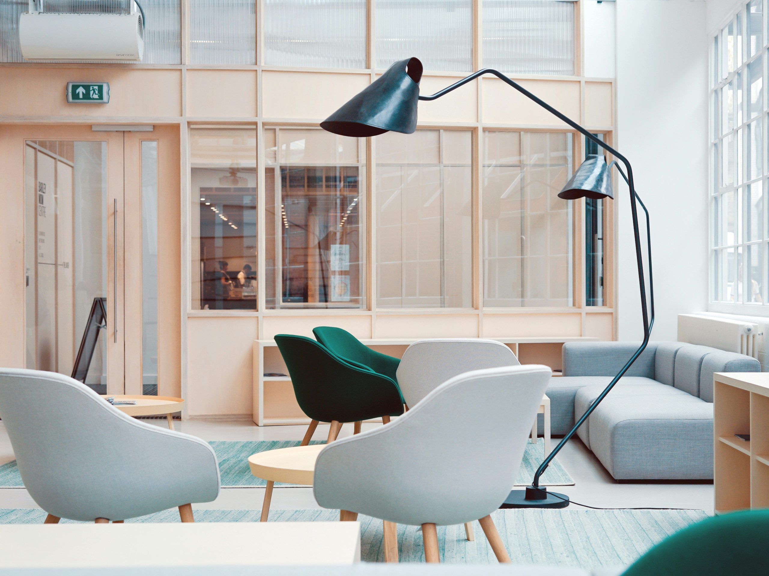 rent kontor med företagsstäd och kontorsstädning stor lampa i mitten. flera fåtöljer i grå och grön med grå soffa.